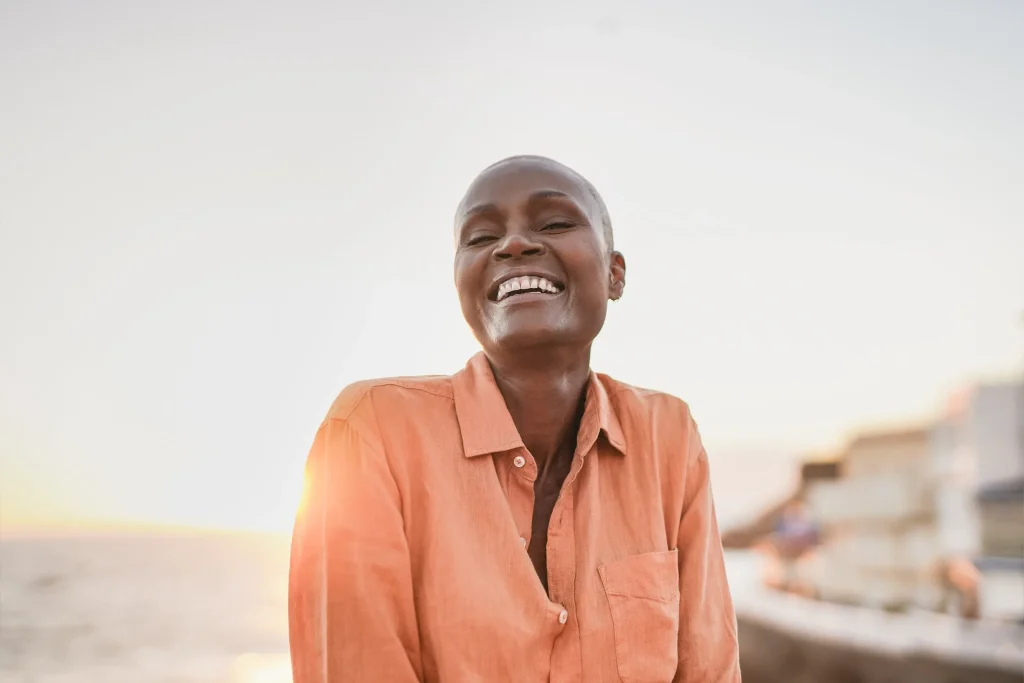 Older woman smiling outdoors in warm light, representing compounded longevity therapies