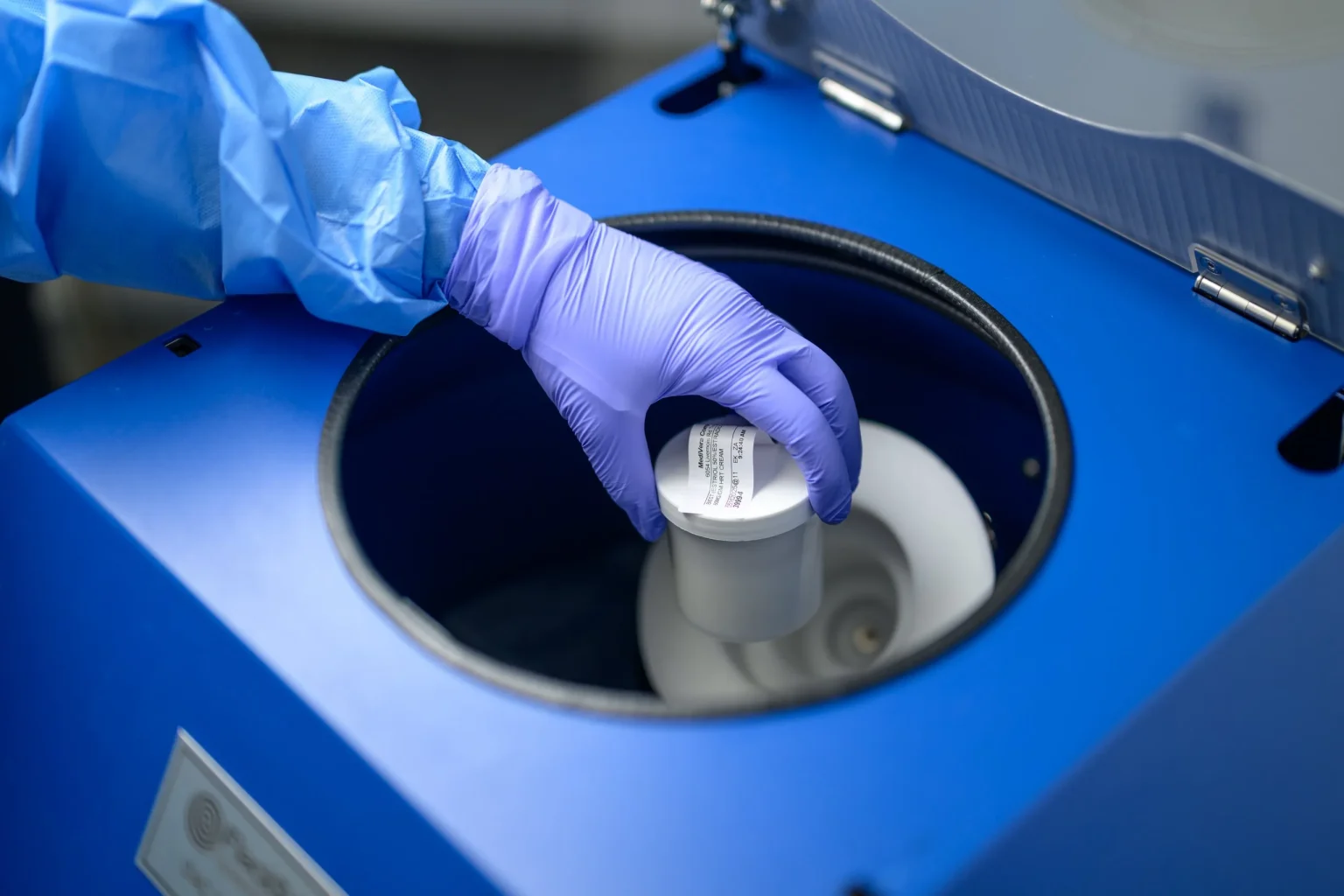Gloved MediVera pharmacist loading a compounded vial into a laboratory mixing chamber