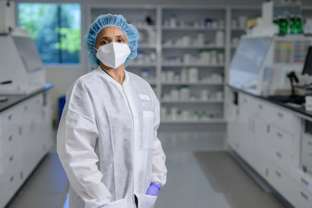 A gowned MediVera pharmacist in hair cover and mask standing in the sterile compounding lab