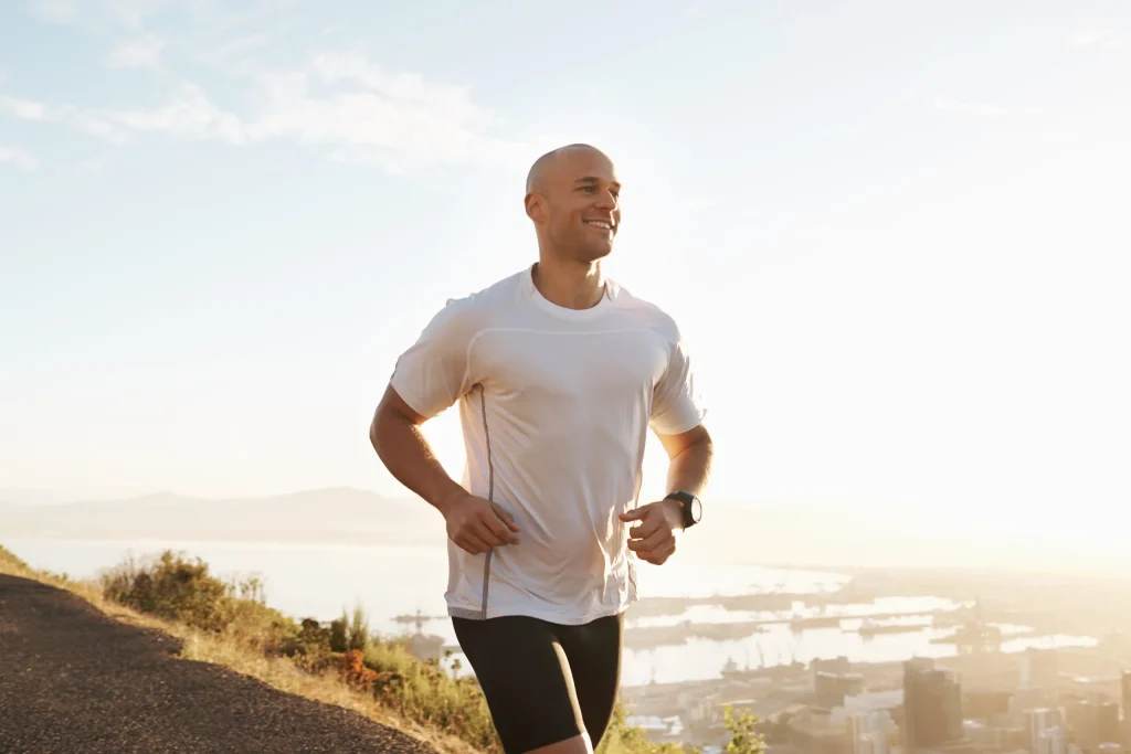 Man jogging on a coastal path, representing compounded men's health treatments