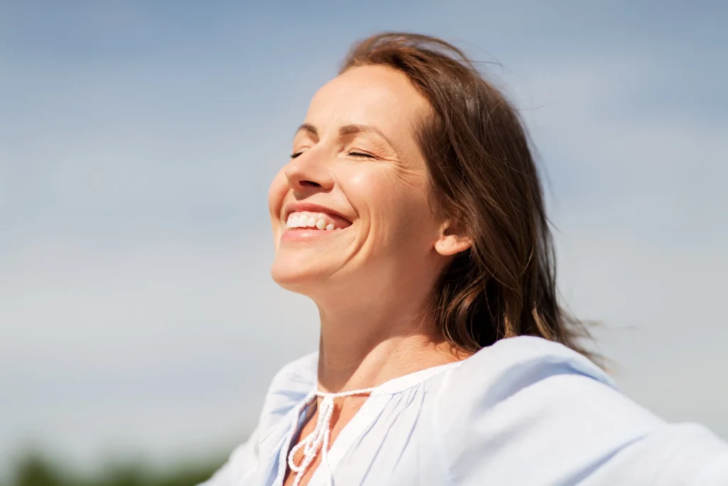 Woman smiling with her face turned to the sun, representing compounded hormone replacement therapy
