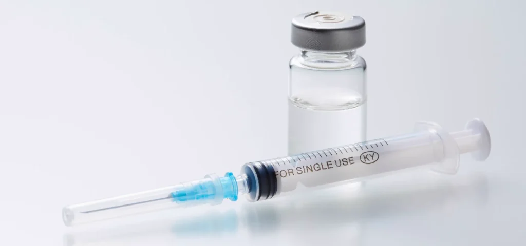 Compounded TriMix injection preparation with vial and syringe in sterile pharmacy environment.