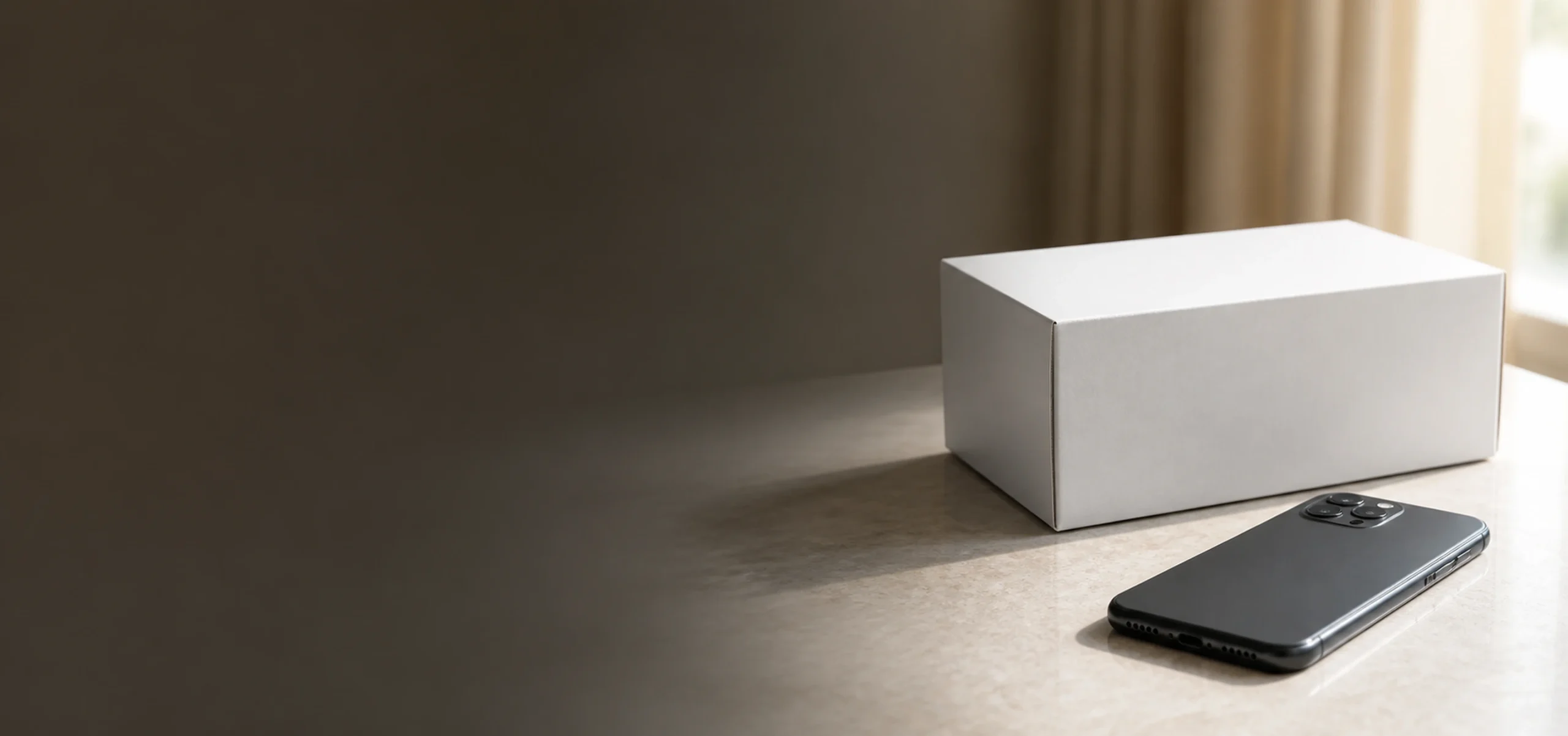 A plain unlabeled parcel and a phone resting on a sunlit table.