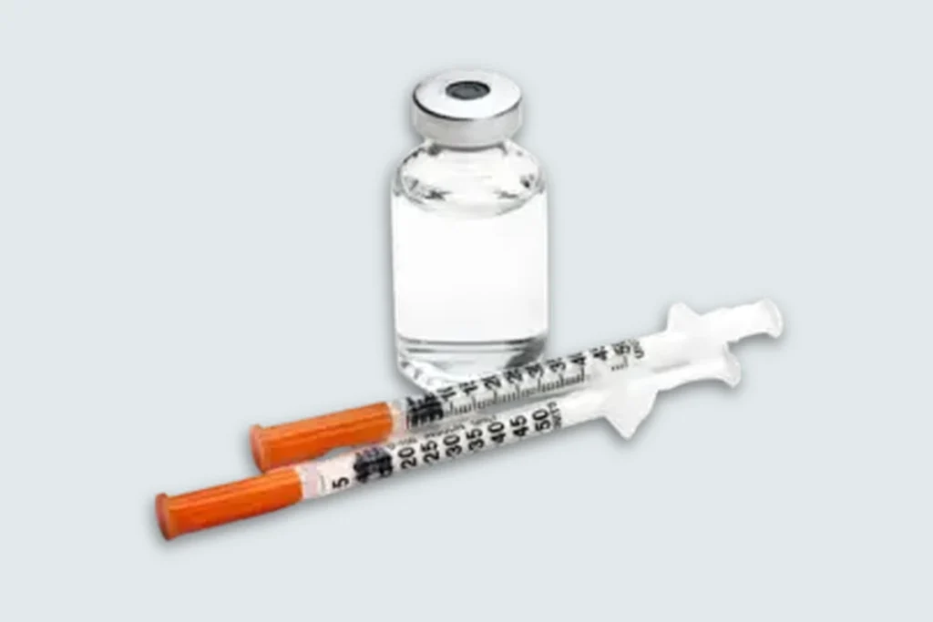 Trimix solution vial with two capped dosing syringes on a pale cool-gray studio background